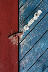 Detail of doorknob an old wooden door painted brightly on a farm in Finland.