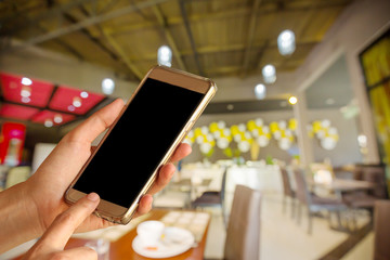 Woman hand hold and touch screen smart phone over blurred restaurant background