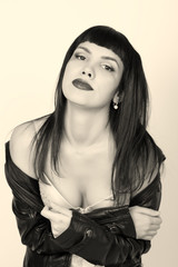 Portrait of beautiful young woman in a leather jacket, standing turned with bare shoulders. posing at camera