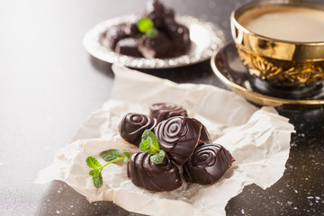 chocolates on paper and coffee on a table, selective focus