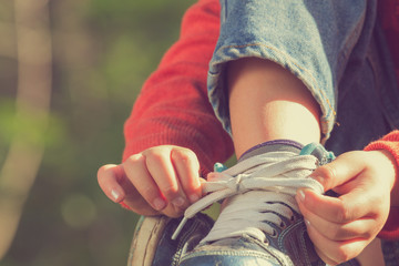 Kid girl tying her shoes. - Powered by Adobe