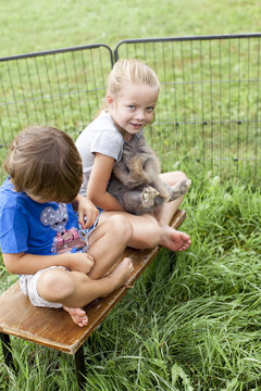 Kinder spielen mit Kaninchen