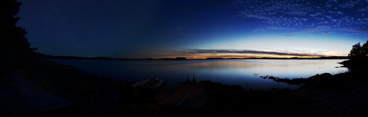 Panorama of a lake at dusk and after nightfall. On the right side sky and lake are illuminated by...