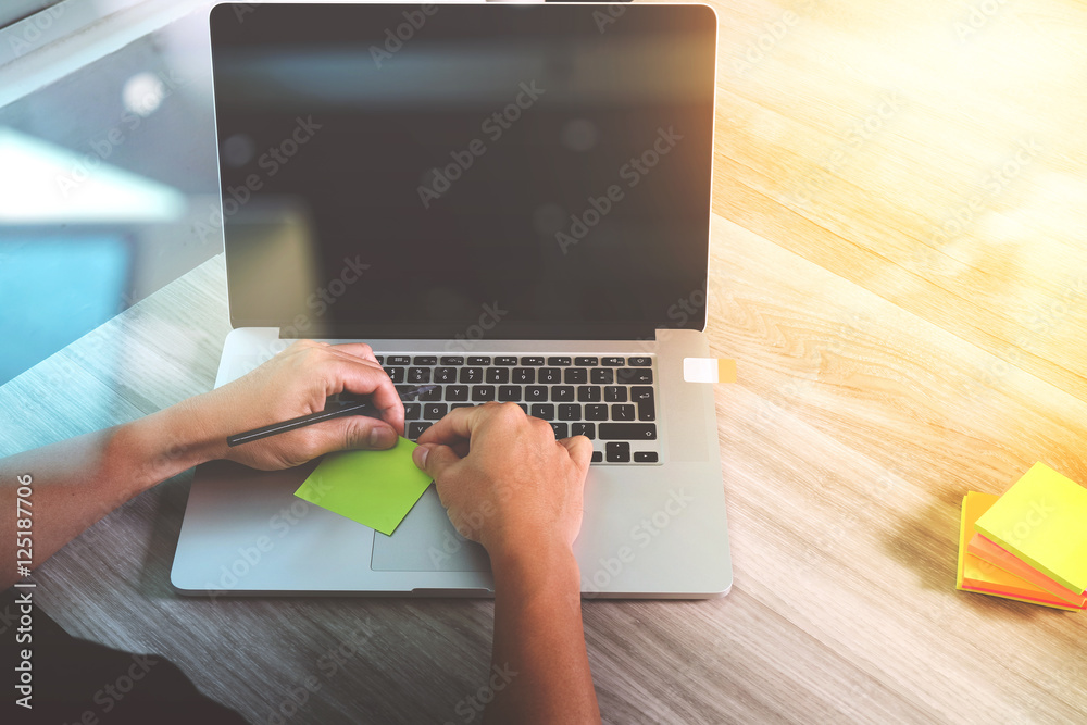 Poster designer hand working with laptop computer on wooden desk as res