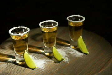 Gold tequila shots with lime and salt on wooden table