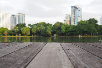 Fototapeta na wymiar Defocus and blur image of terrace wood and water, trees and building inside. Park view in the city, natural background