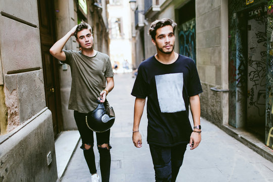 Two Young Men Walking In The Street.
