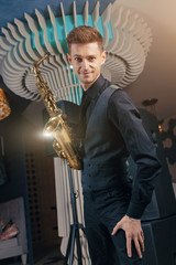 Young man plays a musical instrument saxophone. Saxophone instrument for jazz.