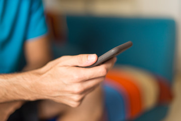 Man in an apartment writing a messege with mobile