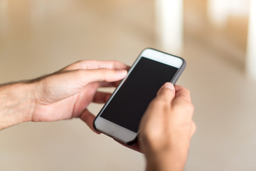 Man in an apartment writing a messege with mobile
