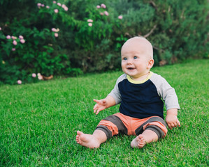 Happy adorable baby boy sitting on the grass