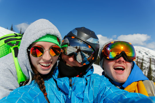 Group of happy friends snowboarding doing selfie
