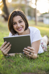 Obraz premium Young woman using tablet in park