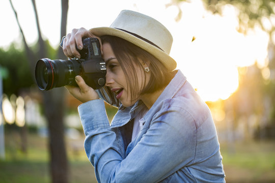 Young woman making photos with professional camera at summer gre