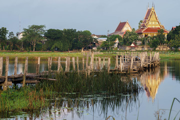 Fototapeta premium Old wooden long bridge cross the lake,Kae Dam District,Thailand