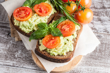 Avocado toast, cherry tomato on wooden background. Breakfast with toast avocado, vegetarian food, healthy diet concept.