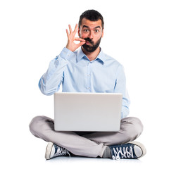 Man with laptop making silence gesture