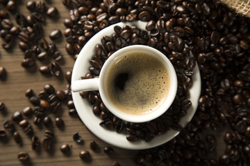 Coffee cup and coffee beans on wooden background. Top view.