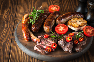 Close-up photo of mixed grilled meat platter. Beef, pork, poultry, sausages, grilled garlic, chili...