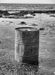 Obraz premium Rusty oil barrel near the shore of the sea