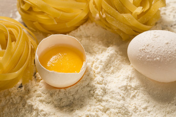 Raw homemade pasta and ingredients for pasta on wooden background