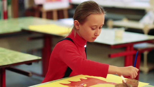 The girl draws a picture paints in classroom