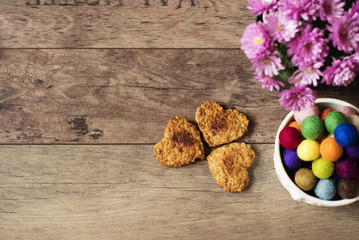 Heart shaped cookies. Top view of homemade cookies, flower chrysanthemum and colorful marbles. Healthy dessert with cinnamon, dates and walnuts. Rustic wooden background