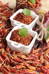Chili powder and dried peppers on wood background.