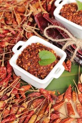 Chili powder and dried peppers on wood background.