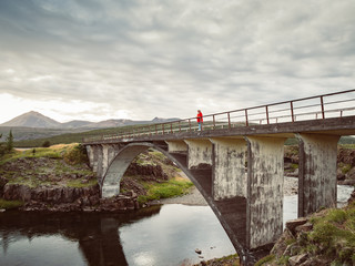 Senior woman is standing on an old bridge in Iceland