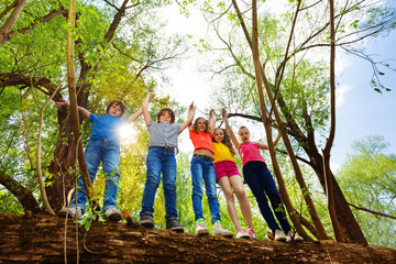 Happy kids standing on fallen tree in the forest