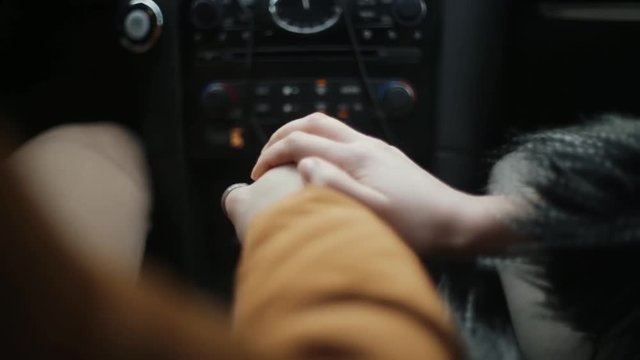 Close-up of lovers hands. Man and woman sitting in a car. People support each other, express love.