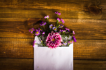 Envelope with pink flowers. On wooden background.