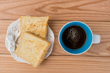 Black coffee and toast on wood background