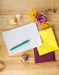 Naklejka na ściany i meble Letter and colorful envelopes. Flowers, pen shells. On wooden background.