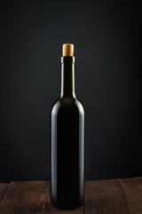 Bottle of red wine. On a wooden table. On a black background.