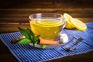 Tea with lemon. Refined sugar, mint, cinnamon on a napkin. On a wooden background.