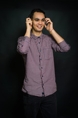 The guy in a shirt, listening to music on headphones. On a black background.
