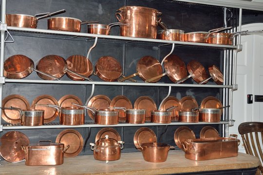 Four shelves of Antique copper cookware