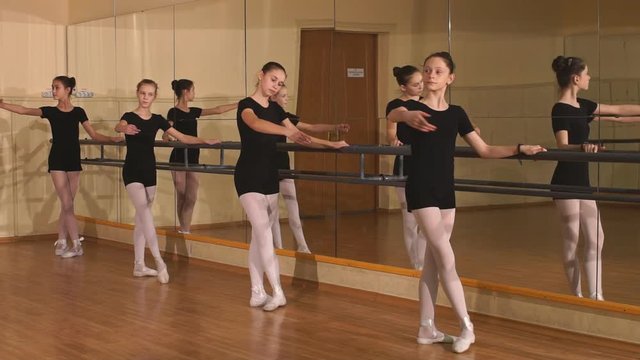 group of eight young ballerinas standing in row and practicing ballet. girls, dancer exercises in a training hall