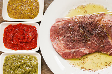 Raw beef steak with three types of sauces. Cooking meat concept.