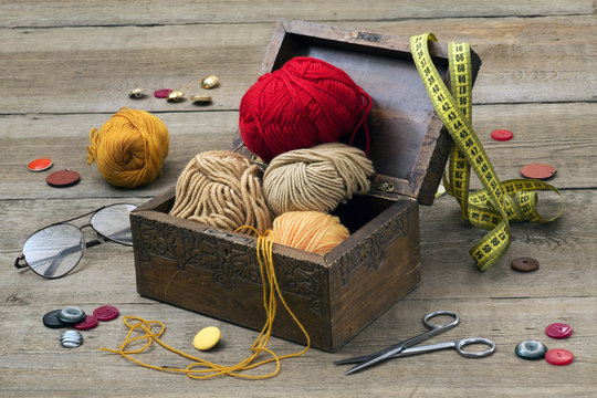 scissors, buttons, yarn, glasses on a wooden table