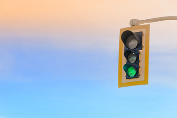 Green traffic light against a sunset sky