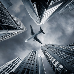 Fototapeta premium Abstract futuristic cityscape view with airplane flying above modern skyscrapers. Hong Kong