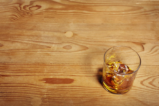 Glass of Whisky with ice on old wooden table