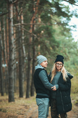 Portrait of young couple in love walking in beautiful forest enjoying hugging and smiling. Feelings, togetherness,friendship