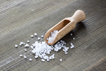 salt crystals with wooden scoop on wooden table