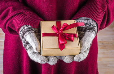 Female hands in winter gloves with christmas gift box