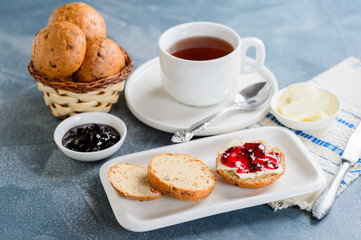 Scones with butter and jam with tea on the table