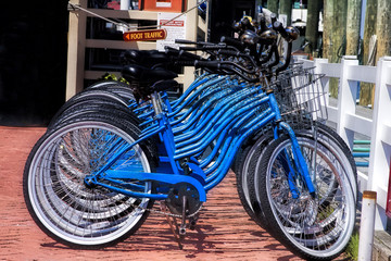 Fototapeta na wymiar Rental blue bikes lined up on boardwalk at the beach. Available for renting.